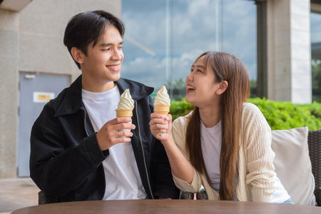 Couple holding and eating ice cream outdoors during summer outdoorsの写真素材