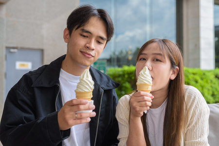 Couple holding and eating ice cream outdoors during summer outdoorsの写真素材