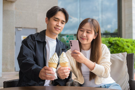 Couple holding and eating ice cream outdoors during summer outdoorsの写真素材