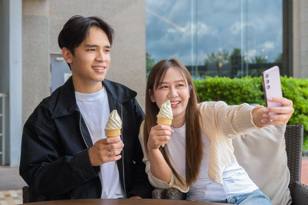 Couple holding and eating ice cream outdoors during summer outdoorsの写真素材