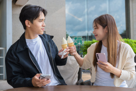 Couple holding and eating ice cream outdoors during summer outdoorsの写真素材
