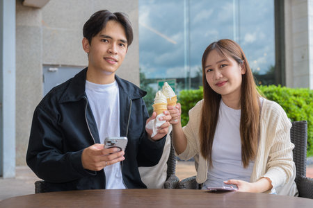 Couple holding and eating ice cream outdoors during summer outdoorsの写真素材