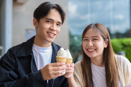 Couple holding and eating ice cream outdoors during summer outdoorsの写真素材