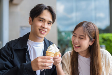 Couple holding and eating ice cream outdoors during summer outdoorsの写真素材