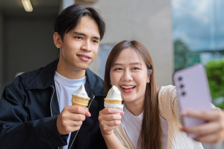 Couple holding and eating ice cream outdoors during summer outdoorsの写真素材