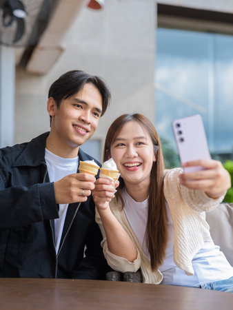 Couple holding and eating ice cream outdoors during summer outdoorsの写真素材