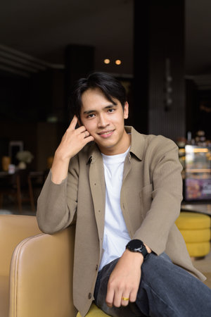 Young Asian businessman sitting in cafe restaurant smiling and looking at cameraの写真素材
