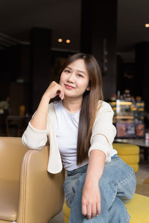 Young Asian businesswoman sitting in cafe restaurant smiling and looking at cameraの写真素材