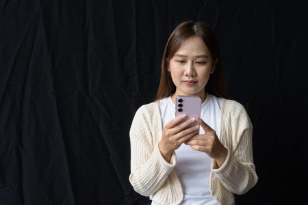 Studio portrait of young Asian woman against dark background