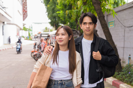 Young Asian tourist couple ordering taxi with mobile app while on street togetherの写真素材