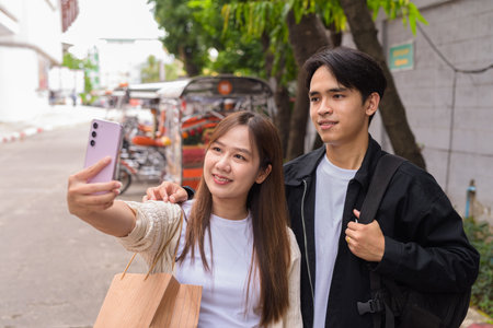 Young Asian tourist couple ordering taxi with mobile app while on street togetherの写真素材