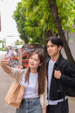 Young Asian tourist couple ordering taxi with mobile app while on street togetherの写真素材