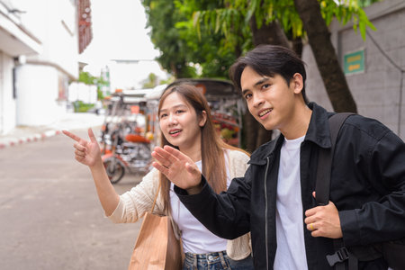 Young Asian tourist couple ordering taxi with mobile app while on street togetherの写真素材