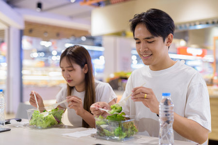 Young couple eating healthy salad indoors togetherの写真素材