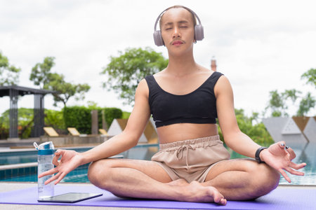 Non-binary Asian person exercising in poolside doing yoga and wearing sport braの写真素材
