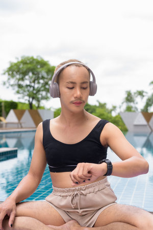 Non-binary Asian person exercising in poolside doing yoga and wearing sport braの写真素材
