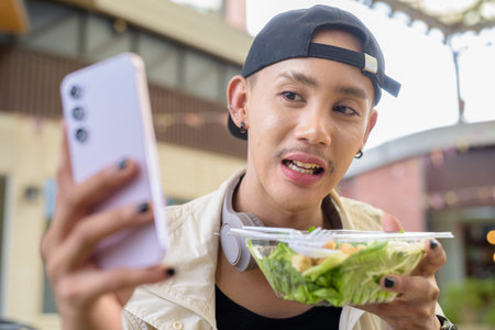 Nonbinary Asian person eating healthy caesar salad outdoors