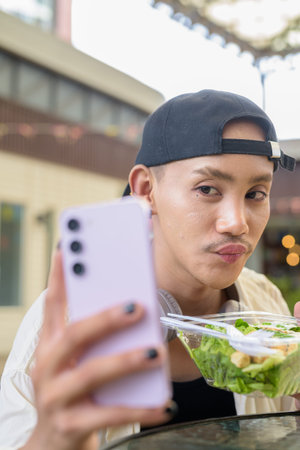 Nonbinary Asian person eating healthy caesar salad outdoors