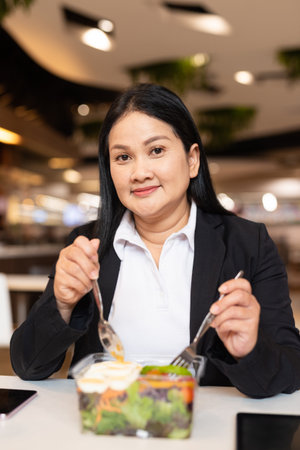 Portrait of woman in business clothes eating salad for lunch in restaurantの写真素材
