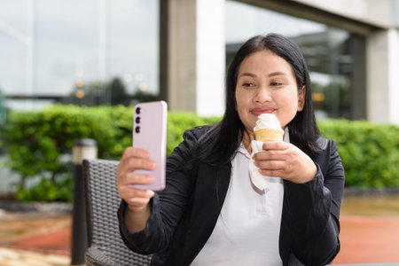 Woman in business clothes eating soft serve ice cream outdoors in restaurant alone
