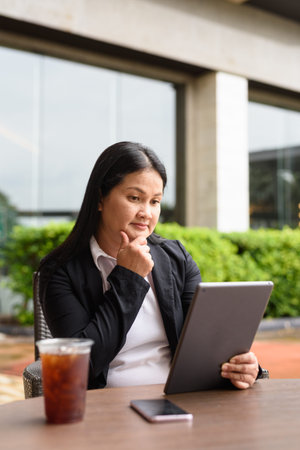 Asian woman sitting and drinking iced coffee outdoors in restaurant
