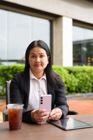 Asian woman sitting and drinking iced coffee outdoors in restaurant