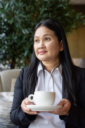 Portrait of Asian businesswoman sitting in cafe restaurant drinking coffee