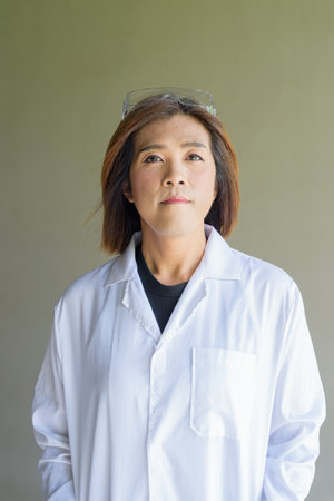 Confident transgender STEM profession non-binary person in lab coat and protective glassesの写真素材