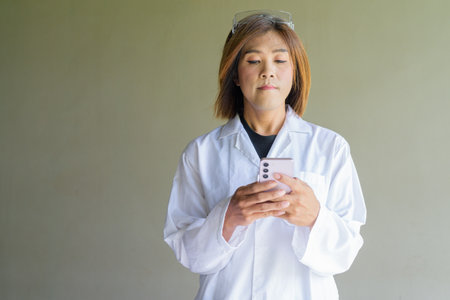 Confident transgender STEM profession non-binary person in lab coat and protective glassesの写真素材