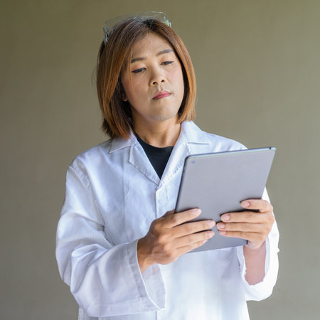 Confident transgender STEM profession non-binary person in lab coat and protective glassesの写真素材