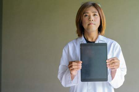 Confident transgender STEM profession non-binary person in lab coat and protective glassesの写真素材