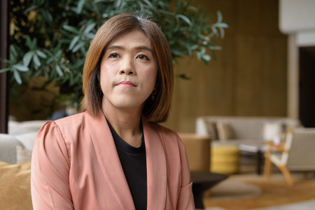 Confident Asian transgender non binary person in business attire at stylish indoor cafe restaurantの写真素材