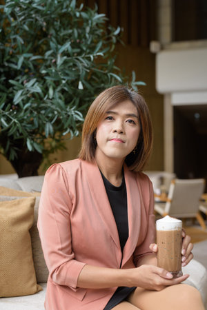 Confident Asian transgender non binary person in business attire at stylish indoor cafe restaurantの写真素材
