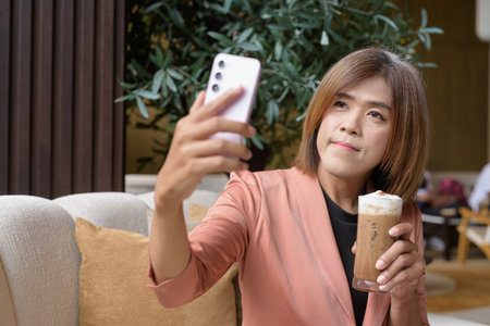 Confident Asian transgender non binary person in business attire at stylish indoor cafe restaurantの写真素材