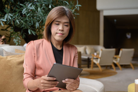 Confident Asian transgender non binary person in business attire at stylish indoor cafe restaurantの写真素材