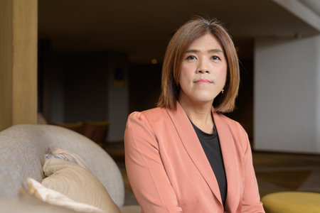 Confident Asian transgender non binary person in business attire at stylish indoor cafe restaurantの写真素材