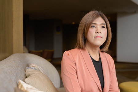 Confident Asian transgender non binary person in business attire at stylish indoor cafe restaurantの写真素材