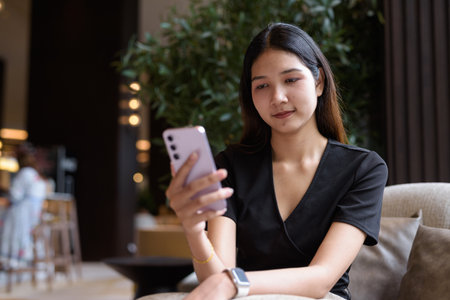 Young Asian woman sitting in coffee shop wearing stylish black dressの写真素材