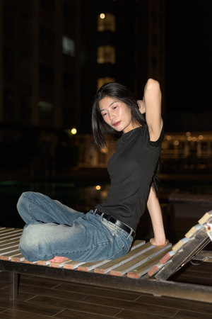 Portrait of beautiful young Asian woman at night at pool during holidayの写真素材