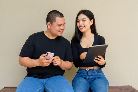 Portrait of young Asian couple against plain wall background