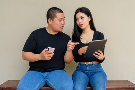Portrait of young Asian couple against plain wall backgroundの写真素材