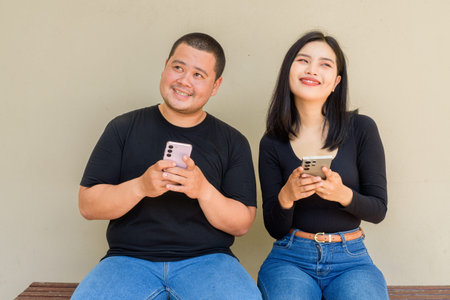 Portrait of young Asian couple against plain wall background