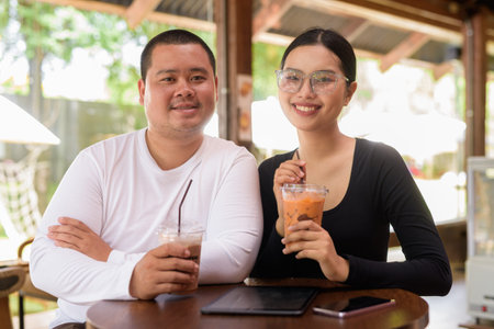 Happy young Asian couple sitting in coffee shop
