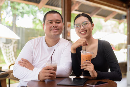 Happy young Asian couple sitting in coffee shop