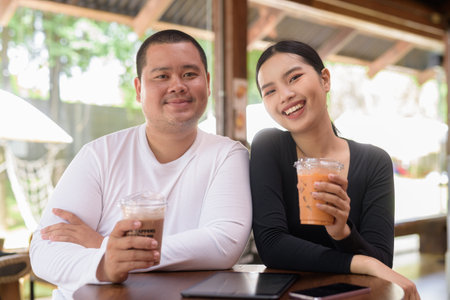 Happy young Asian couple sitting in coffee shopの写真素材