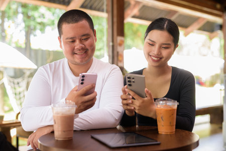 Happy young Asian couple sitting in coffee shopの写真素材