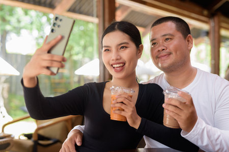 Happy young Asian couple sitting in coffee shopの写真素材