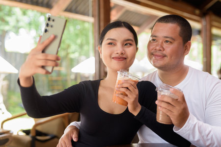 Happy young Asian couple sitting in coffee shopの写真素材