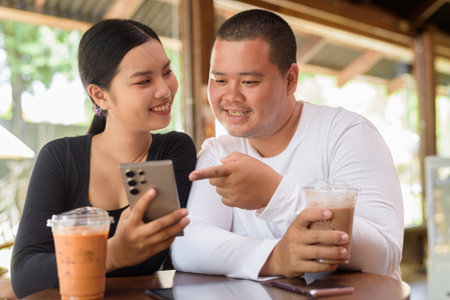Happy young Asian couple sitting in coffee shopの写真素材