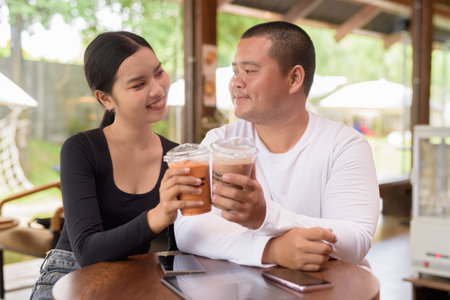 Happy young Asian couple sitting in coffee shopの写真素材